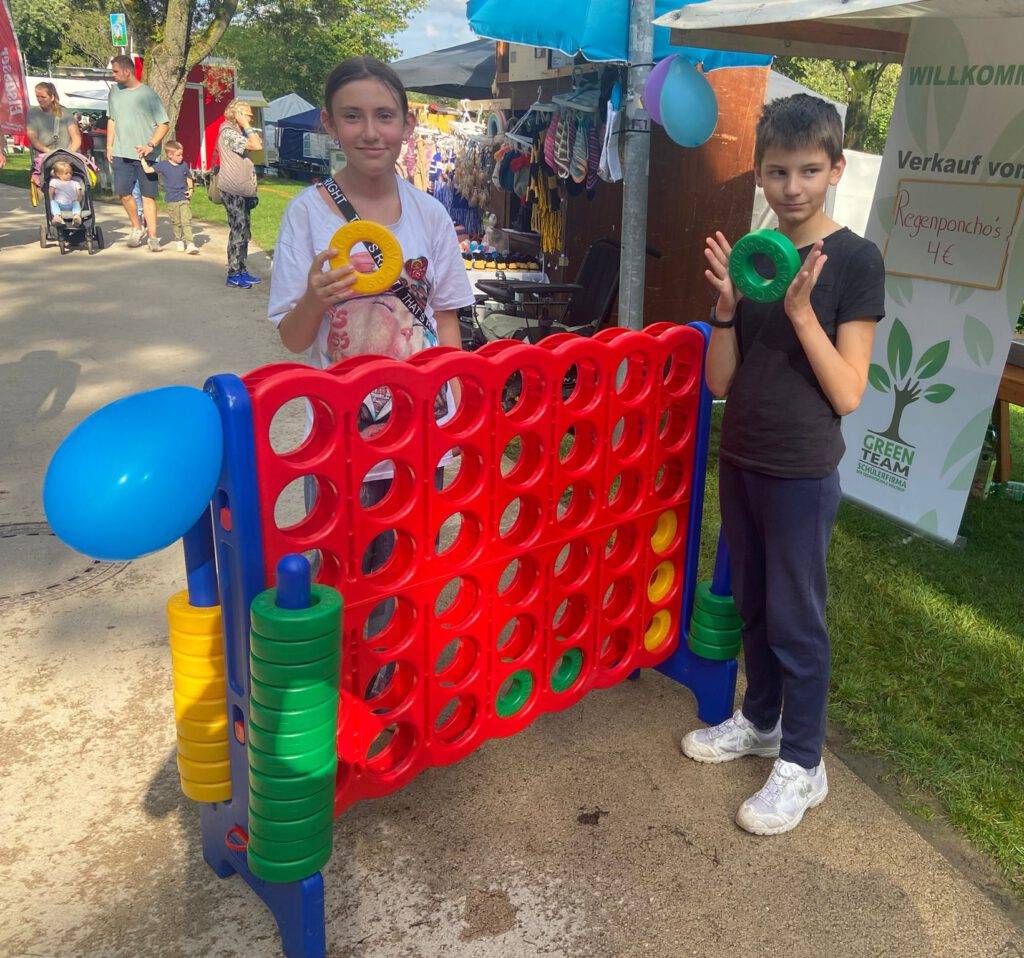 Zwei Kinder spielen mit dem XXL-Spiel 4 Gewinnt auf einer Veranstaltung des GreenTeams